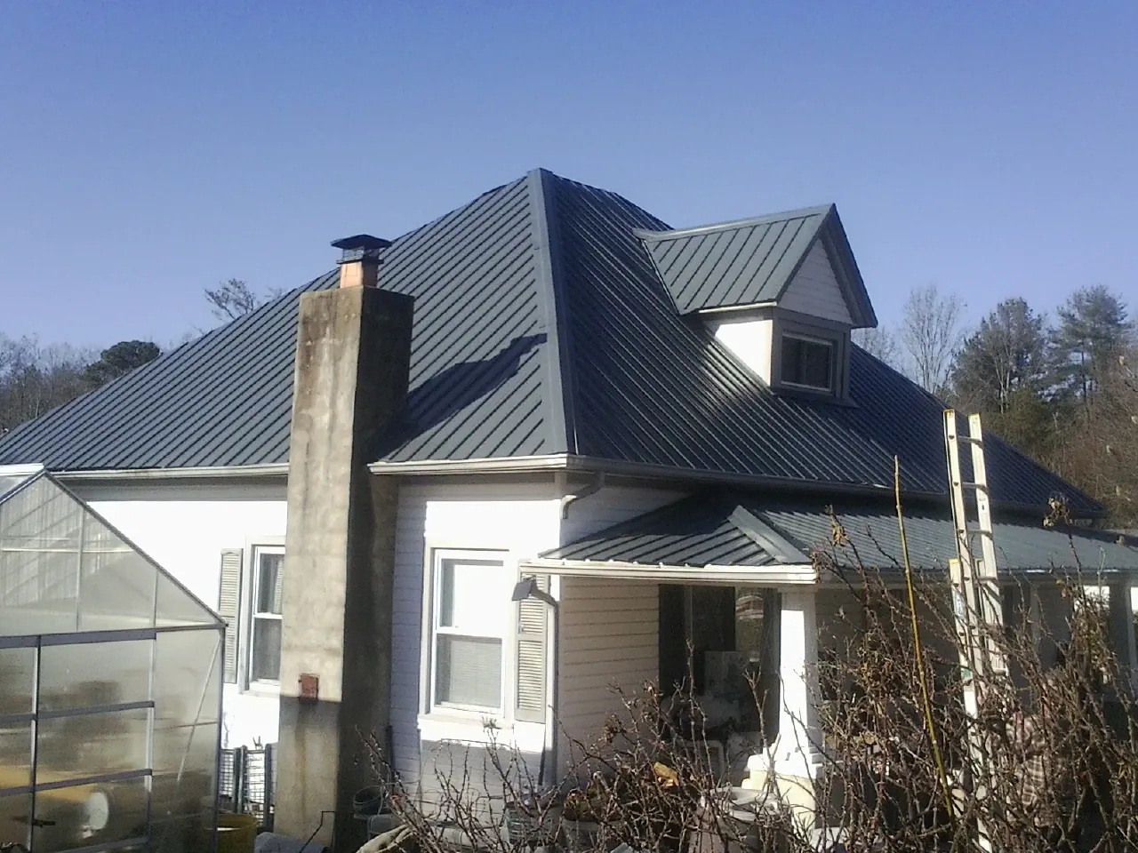 Dark blue standing seam metal roof on a white farmhouse with dormer — Slate & Tile Roof Repair by Roofing Brothers in South Weymouth