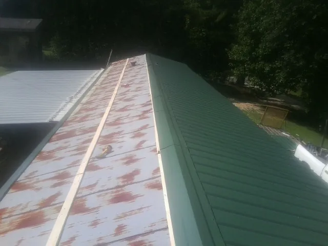 Old rusted panels beside newly installed green metal roofing — Wind Damage Roof Repair by Roofing Brothers in South Weymouth