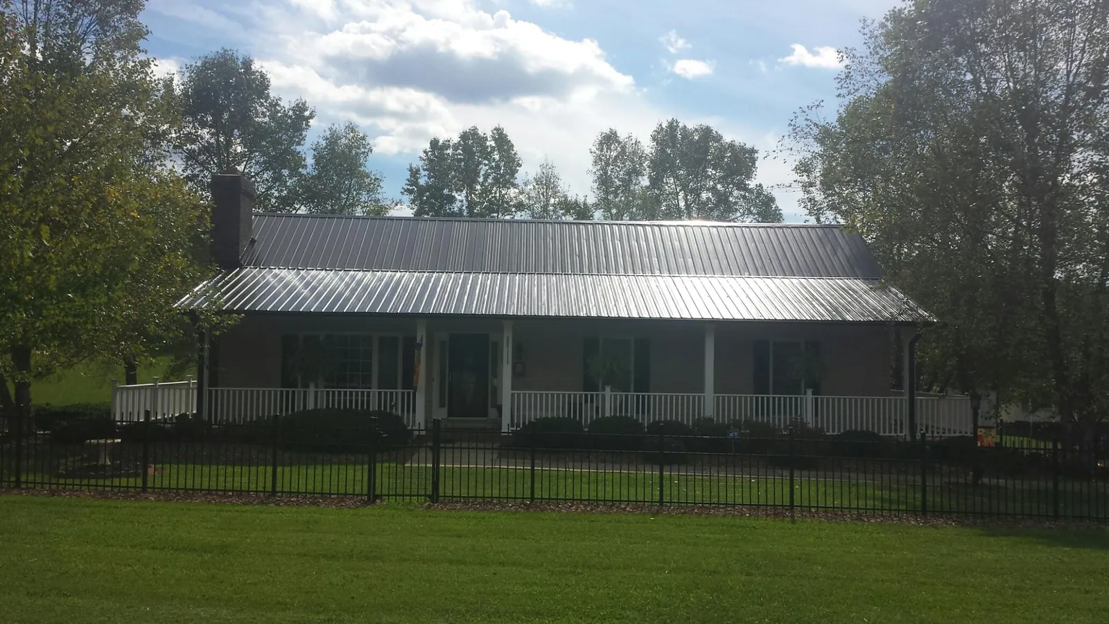 Gray metal roof on a brick ranch with a full width front porch — Gutter Guard Installation work by our crew in South Weymouth