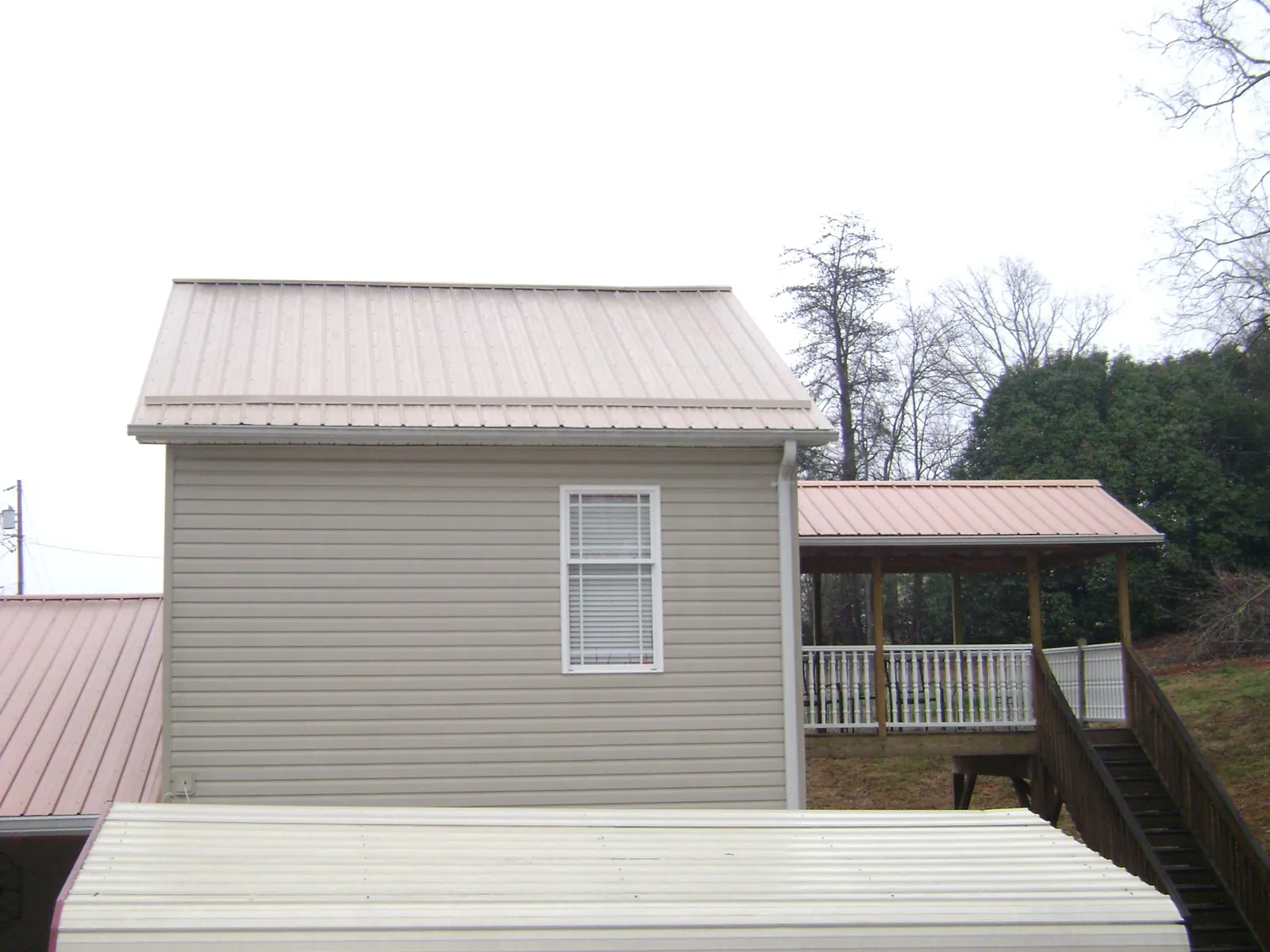 Tan metal roofs on a two story addition and attached porch, from a Roof Replacement job in South Weymouth