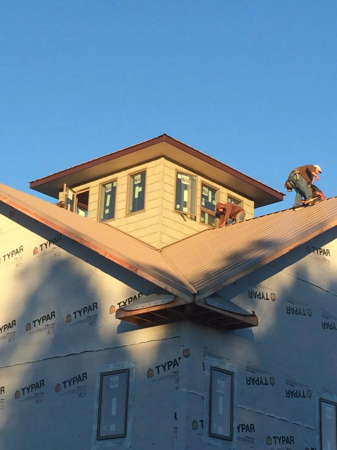 Roofers working around a rooftop cupola on a new metal roof at sunset — Roof Waterproofing in South Weymouth by Roofing Brothers